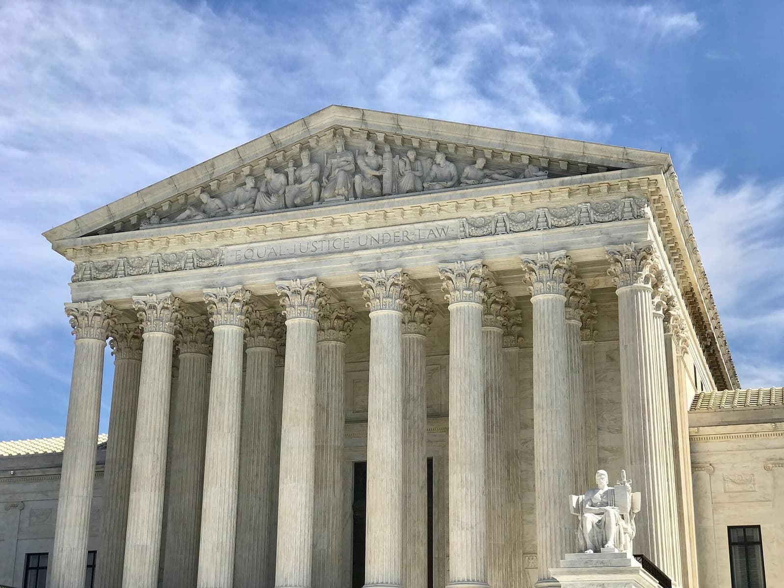 The marble columns and sculpted pediment of the U.S. Supreme Court building, inscribed "Equal Justice Under Law," under a blue sky.